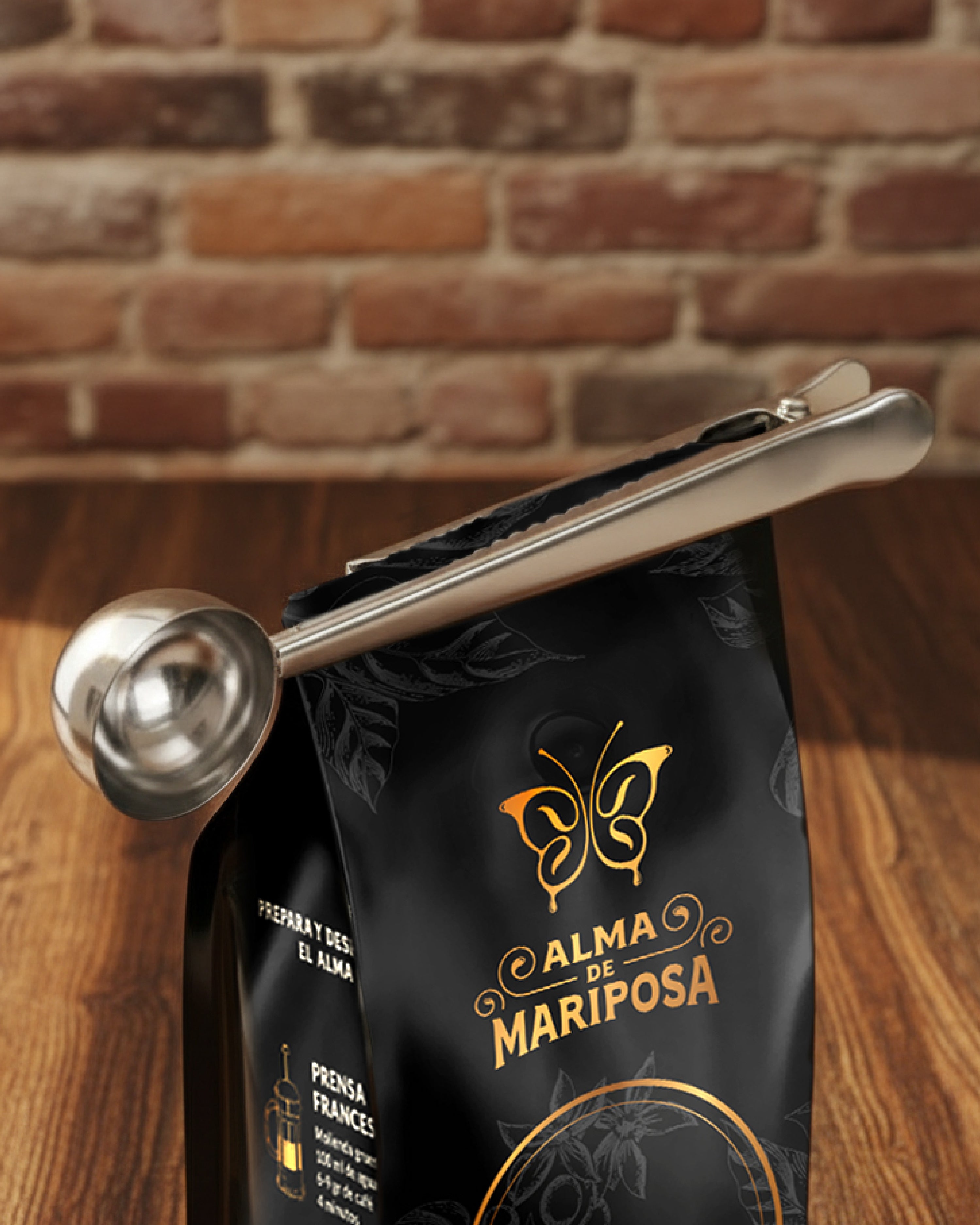 Cuchara medidora de acero inoxidable usando su pinza para sellar una bolsa negra de café de especialidad de la marca Alma de Mariposa.