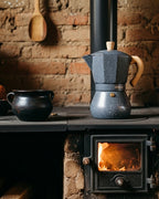 Cafetera Greca Moka sobre estufa de leña tradicional. Preparación de café artesanal en cocina rústica con greca de diseño granito.