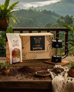 Kit de regalo con Café de Especialidad Typica de Pasca y Prensa Francesa negra de 350ml. Caja de regalo Alma de Mariposa en mesa de madera con paisaje cafetero de fondo.